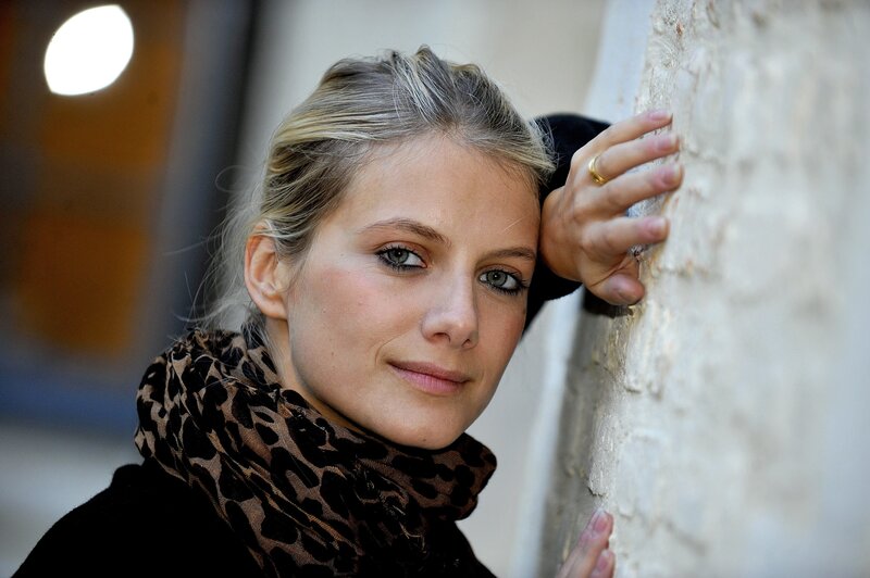 woman with scarf leaning on wall