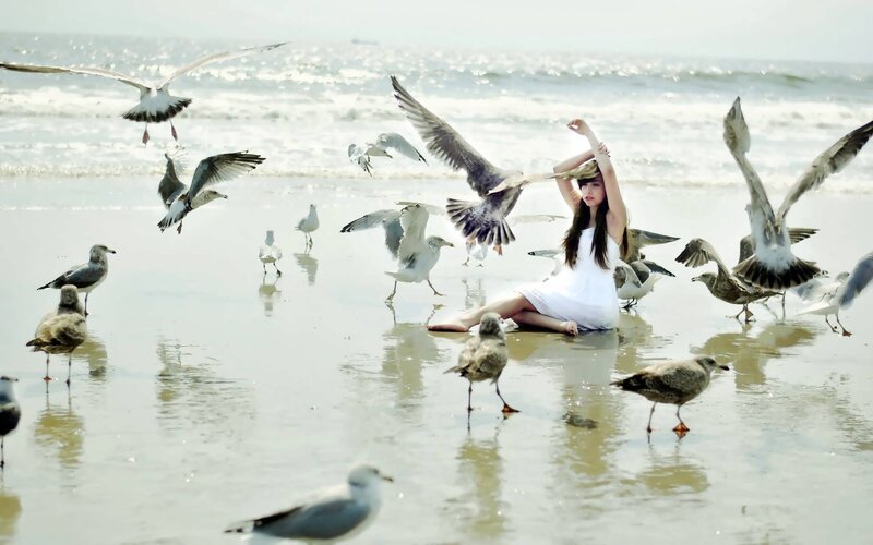 woman with seagulls on beach