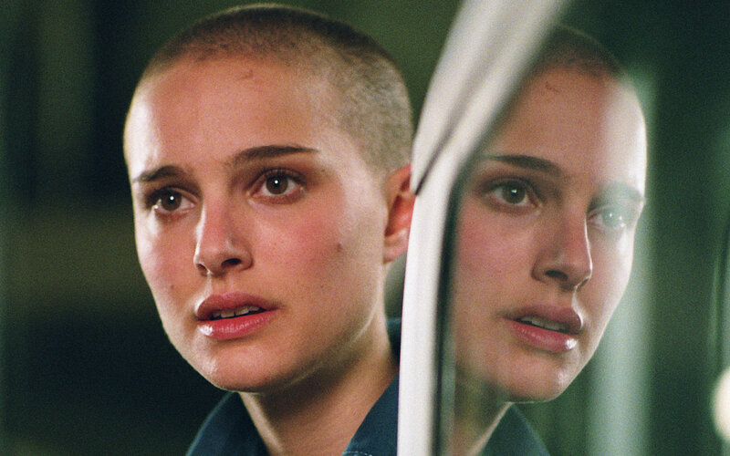 woman with shaved head in mirror