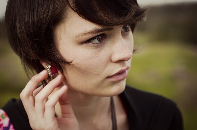 woman with short hair adjusting earring