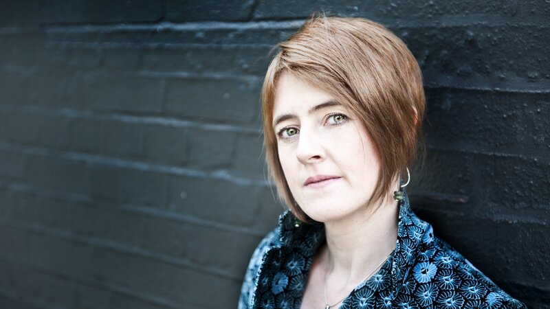 woman with short hair against brick wall