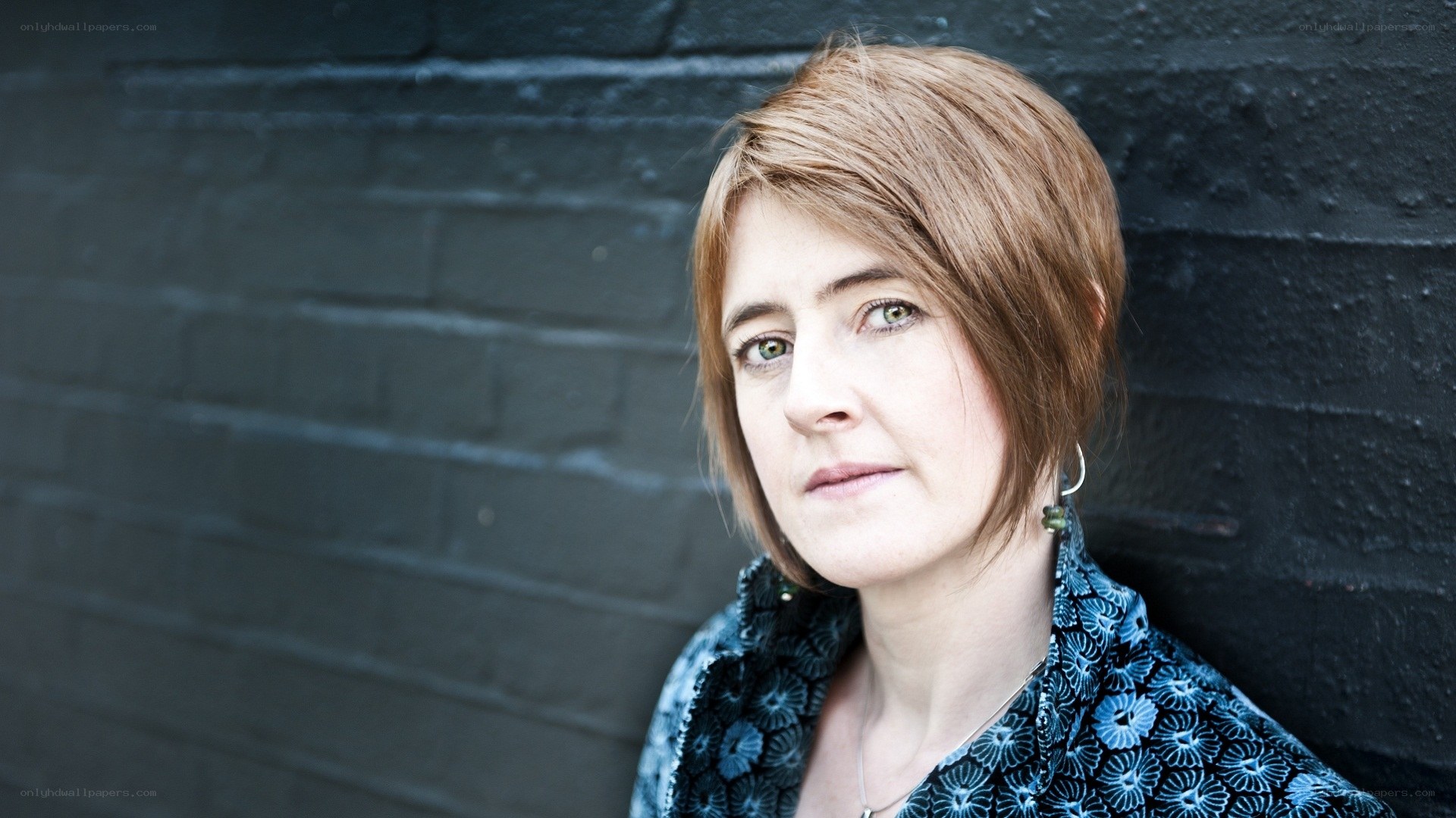 woman with short hair against brick wall