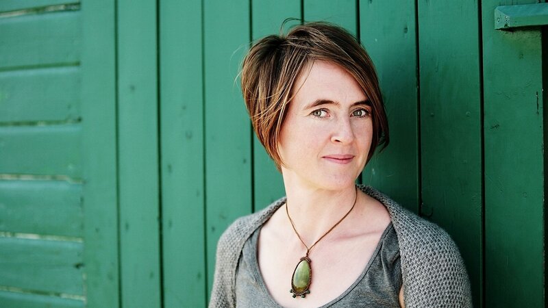 woman with short hair against green wall
