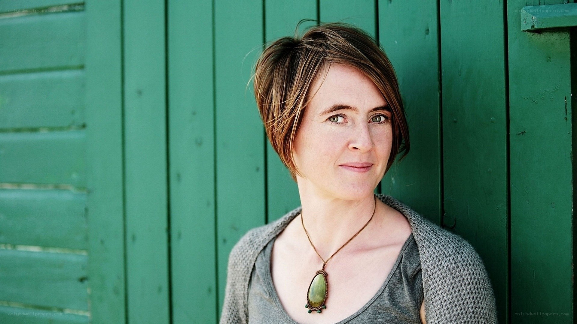 woman with short hair against green wall