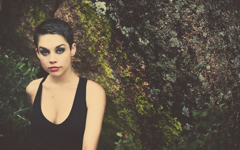 woman with short hair against mossy rock