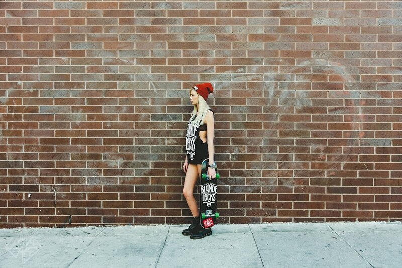 Woman with skateboard against brick wall