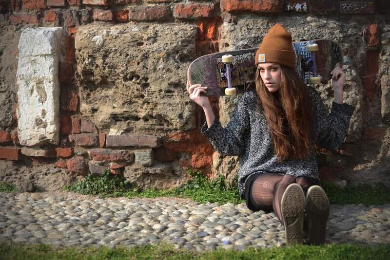 Woman with skateboard against brick wall