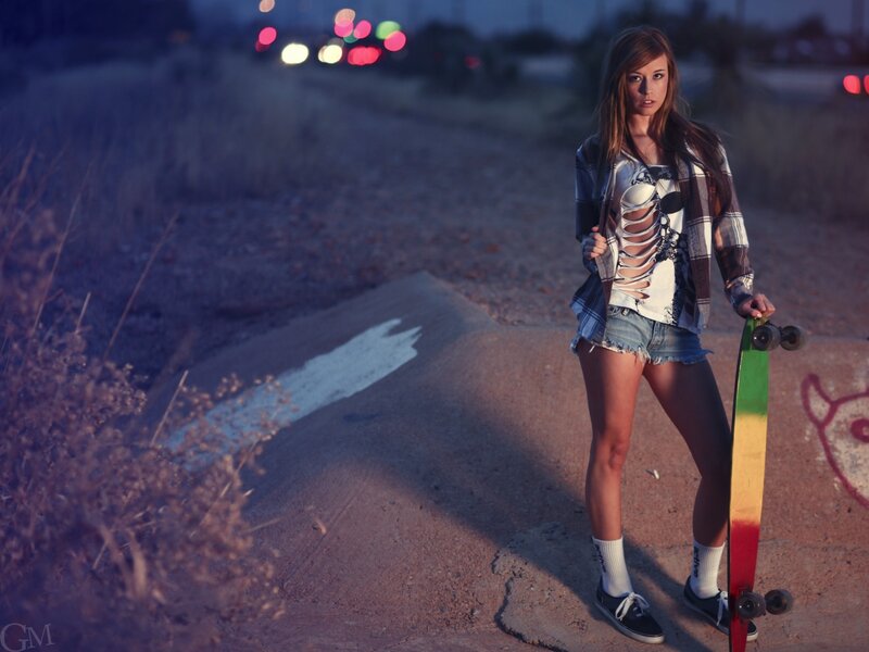 Woman with skateboard at dusk