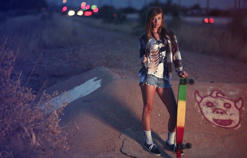 Woman with skateboard at dusk