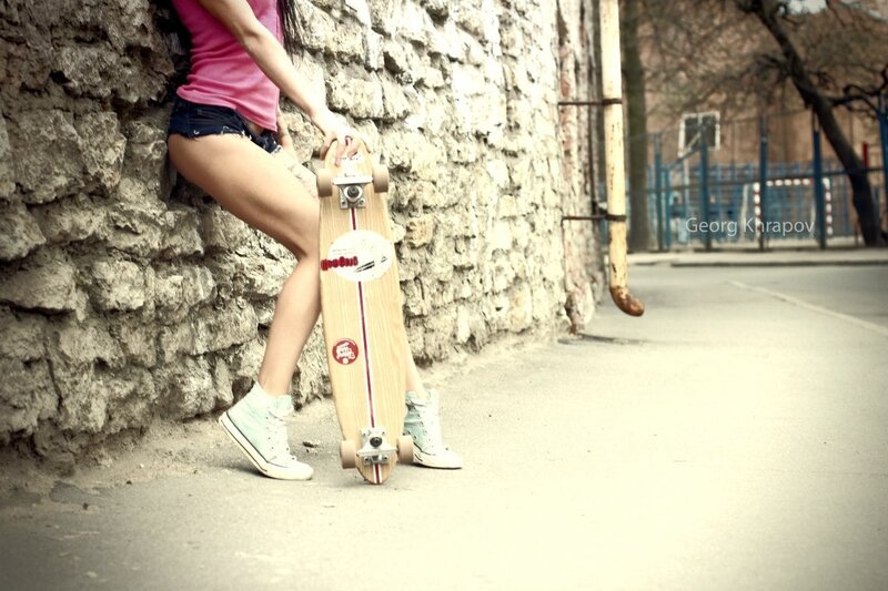 woman with skateboard leaning on wall