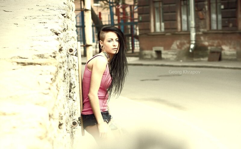 woman with skateboard leaning on wall