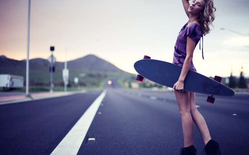woman with skateboard on road