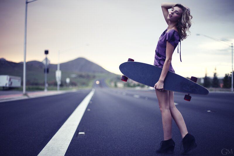 Woman with skateboard on road