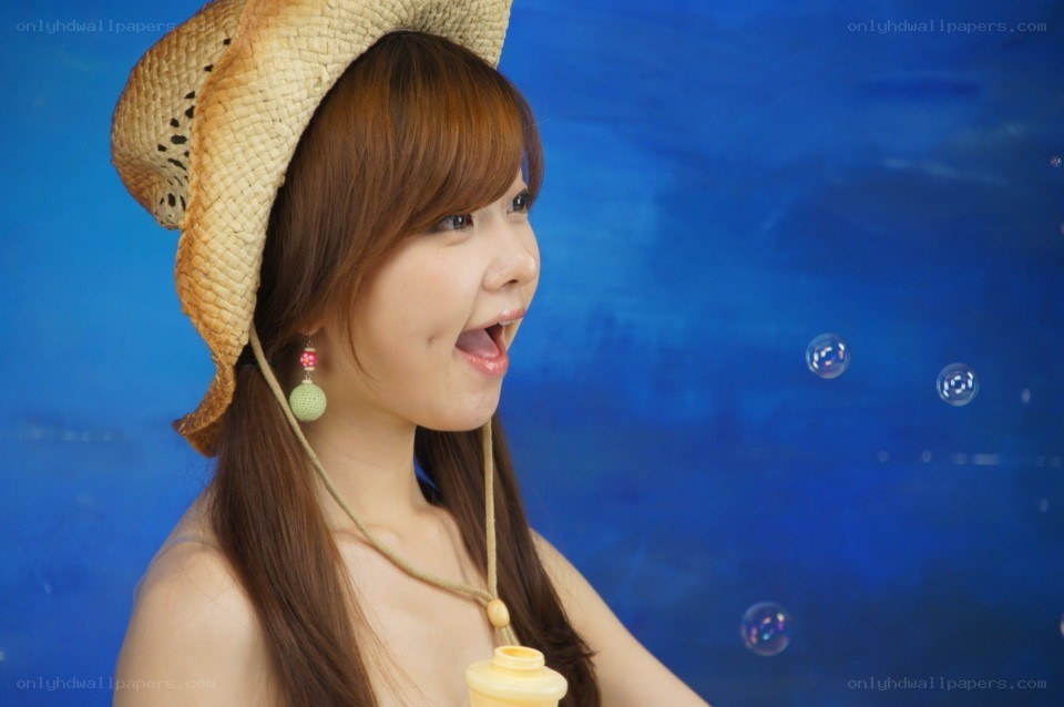woman with straw hat blowing bubbles