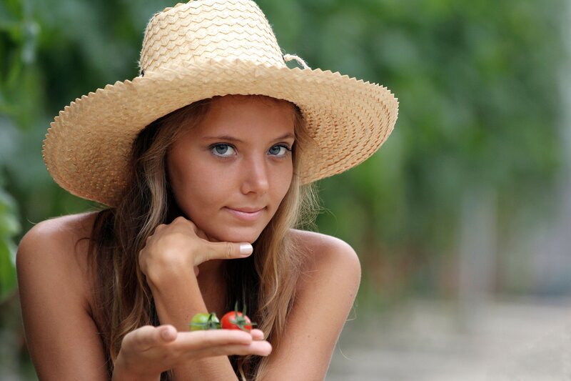 woman with straw hat holding tomatoes
