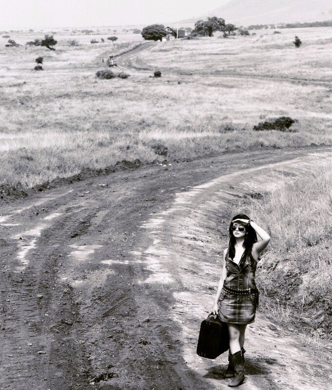 Woman with suitcase on dirt road