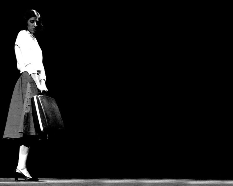 woman with suitcase on stage