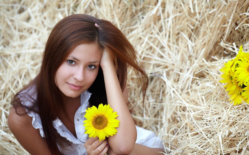 woman with sunflower in hay