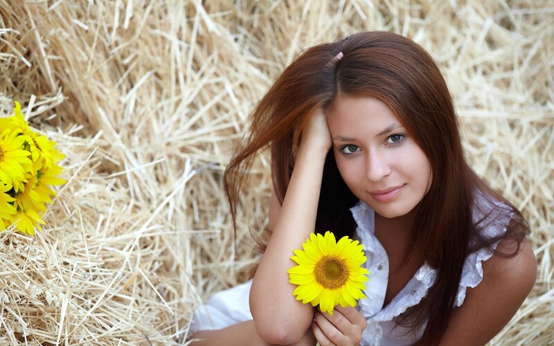 woman with sunflower in hay
