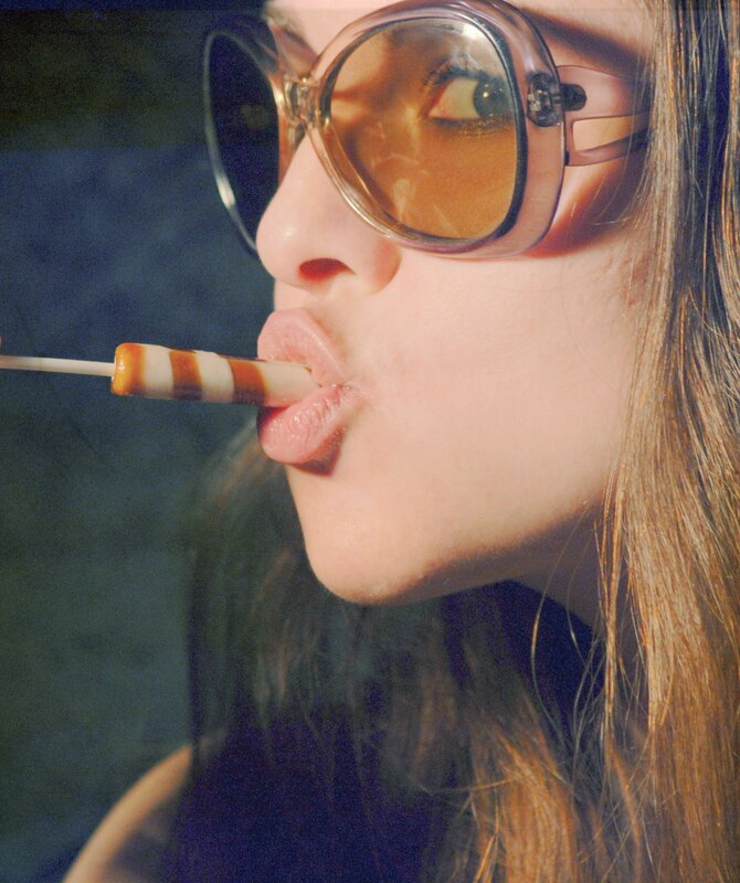 woman with sunglasses licking candy