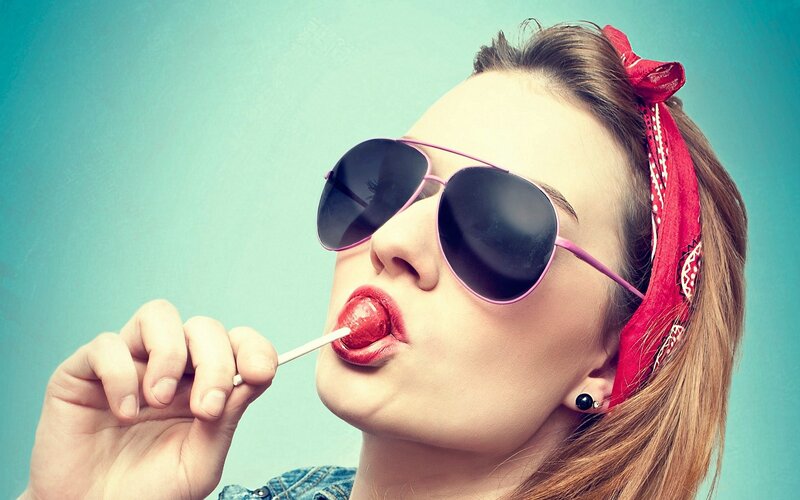 woman with sunglasses licking lollipop