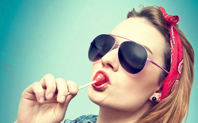 woman with sunglasses licking lollipop
