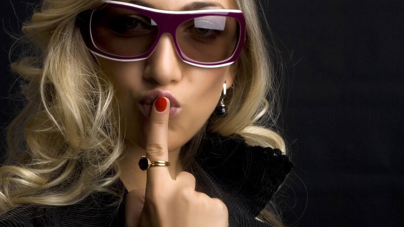 woman with sunglasses making shush gesture