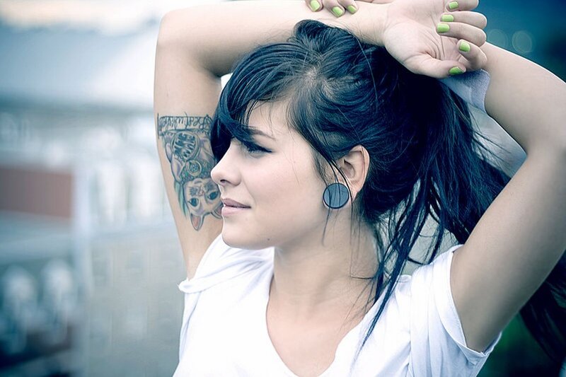 woman with tattoo and ear plugs