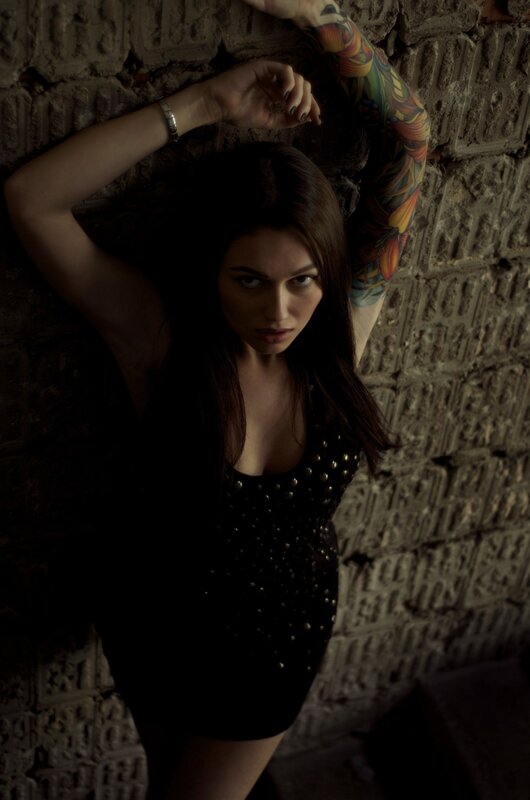 woman with tattoo leaning on wall