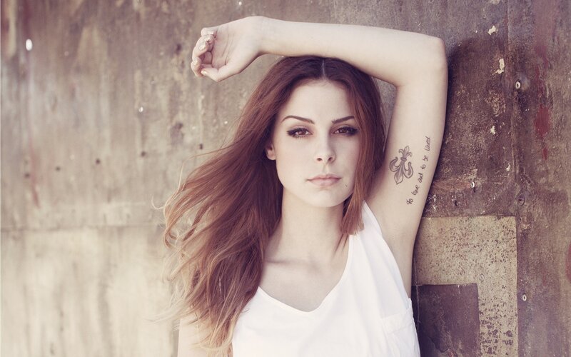 woman with tattoo leaning on wall
