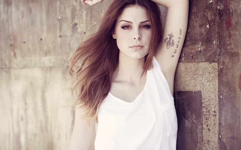 woman with tattoo leaning on wall