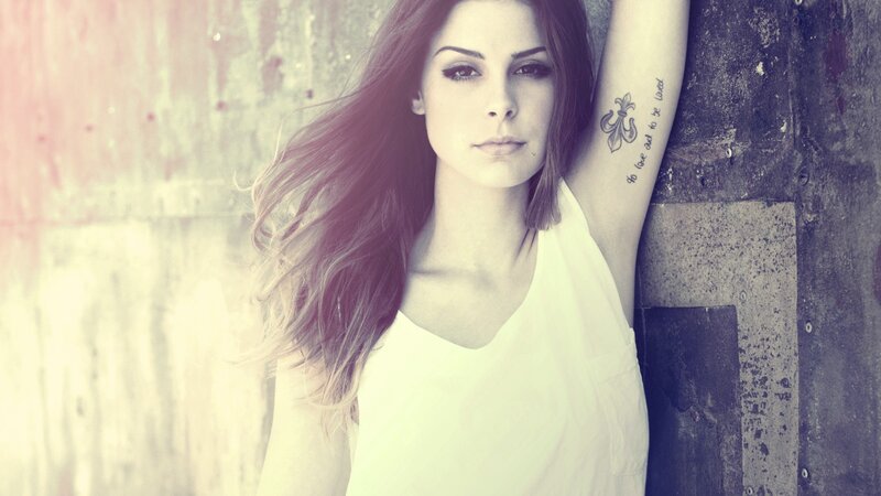 woman with tattoo leaning on wall