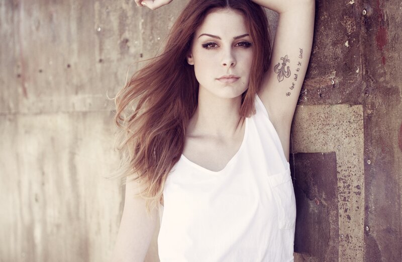 woman with tattoo leaning on wall