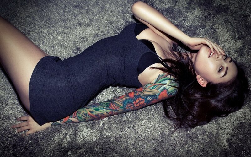 woman with tattoo lying on carpet