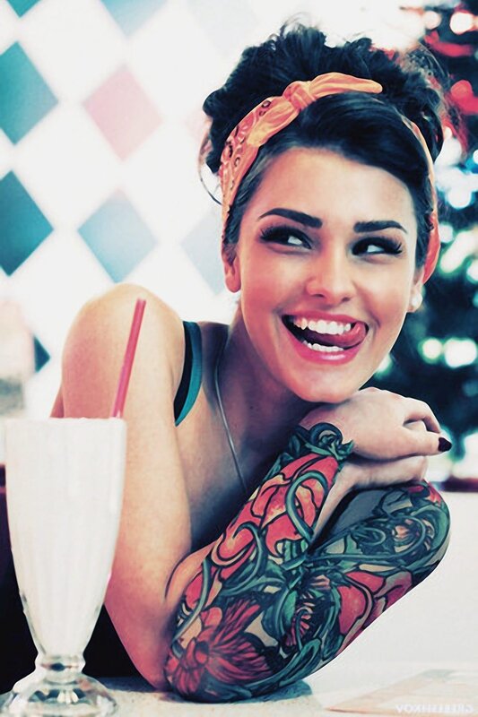 woman with tattoo smiling at milkshake