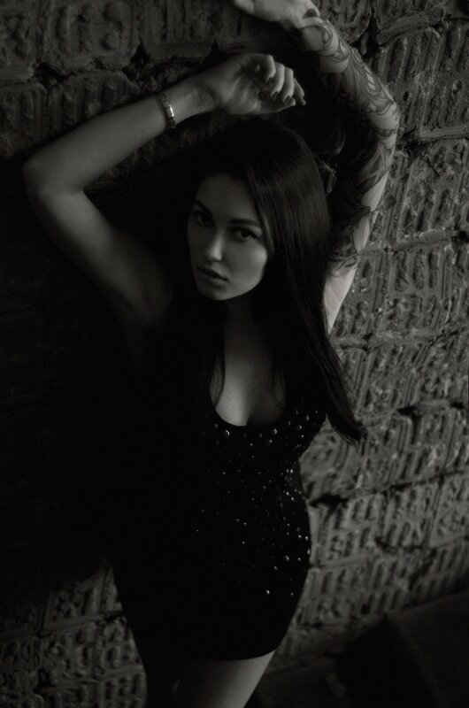 woman with tattoos against brick wall