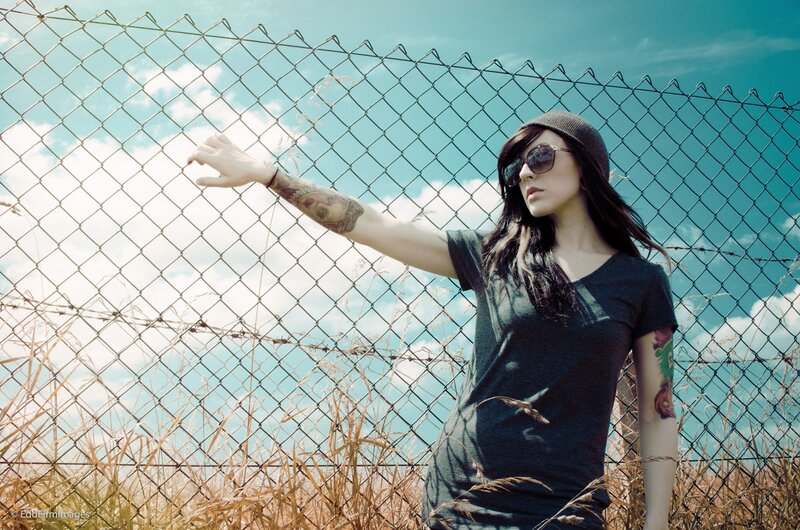 woman with tattoos by fence