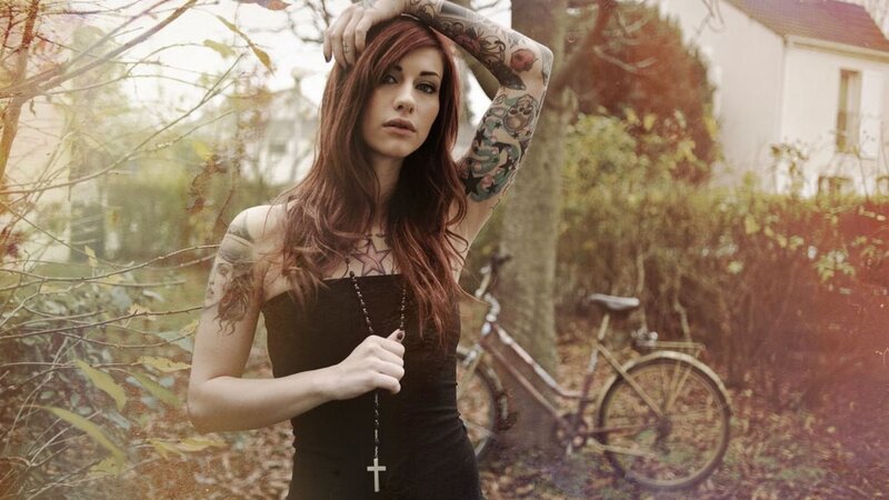 woman with tattoos holding a cross