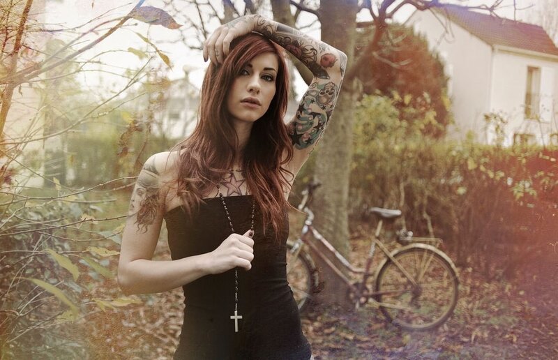 woman with tattoos holding a cross