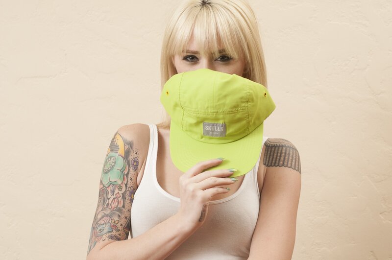 Woman with tattoos holding cap