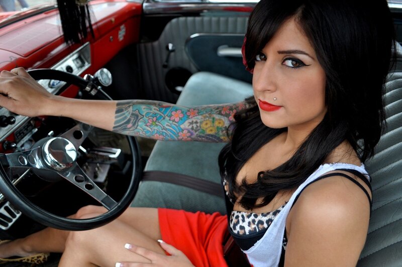 woman with tattoos in red car