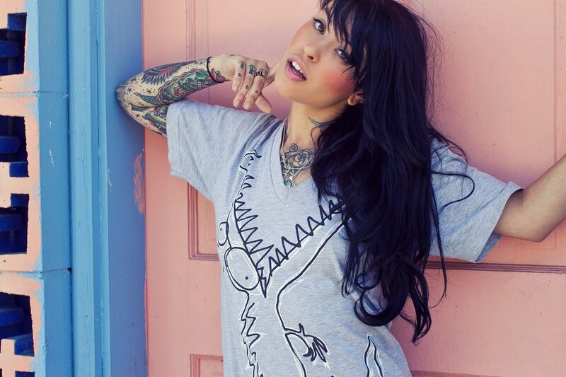woman with tattoos leaning against wall