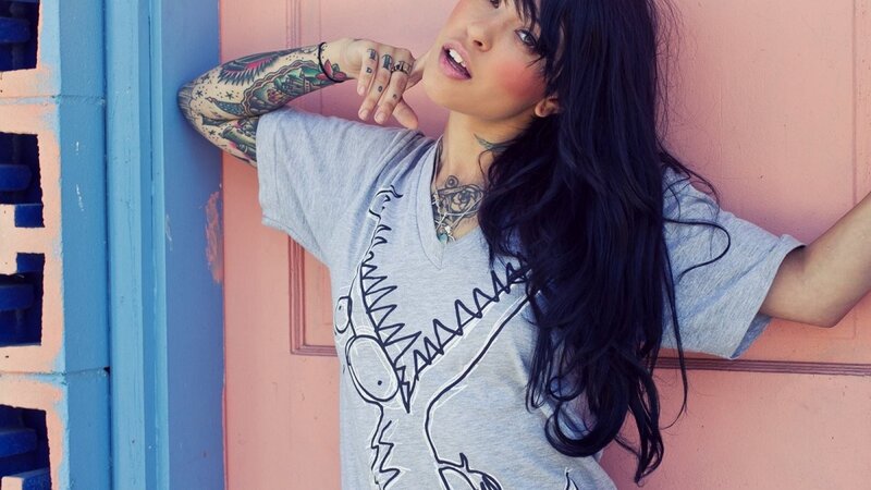woman with tattoos leaning against wall