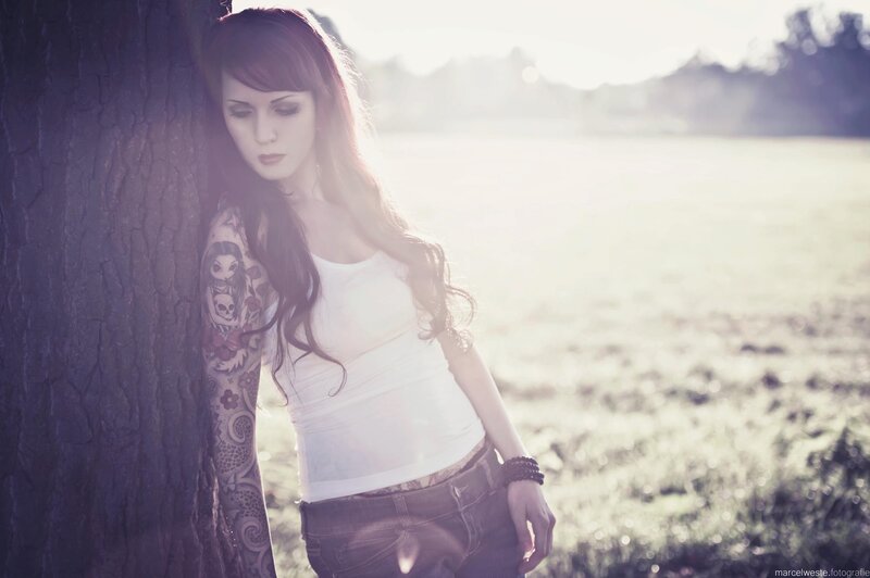 woman with tattoos leaning on tree