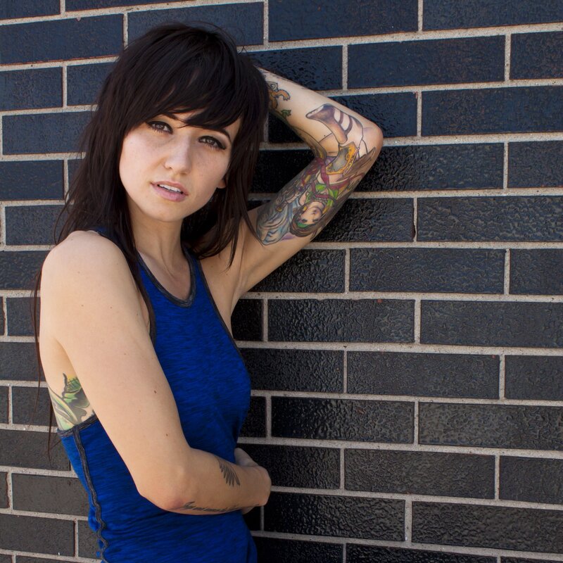 woman with tattoos leaning on wall