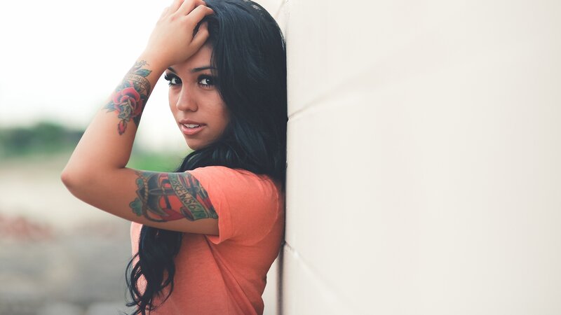 woman with tattoos leaning on wall