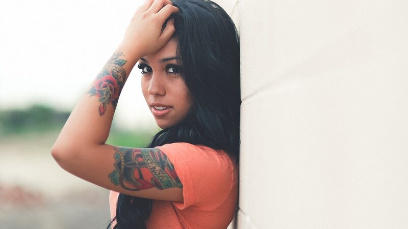 woman with tattoos leaning on wall