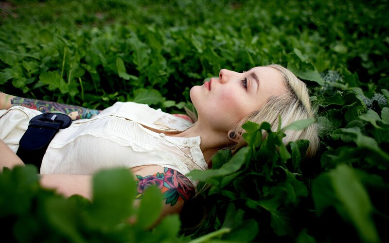 woman with tattoos lying in greenery