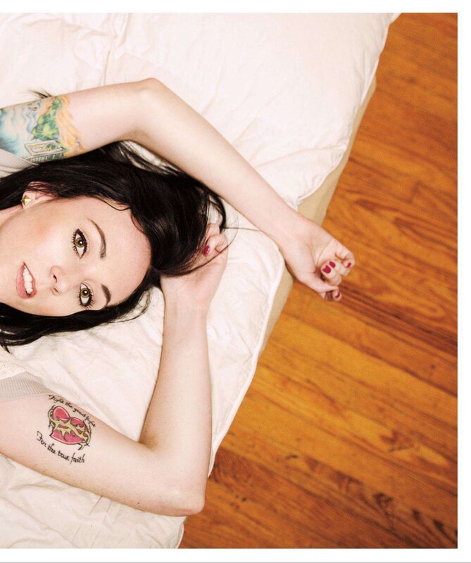 woman with tattoos lying on bed
