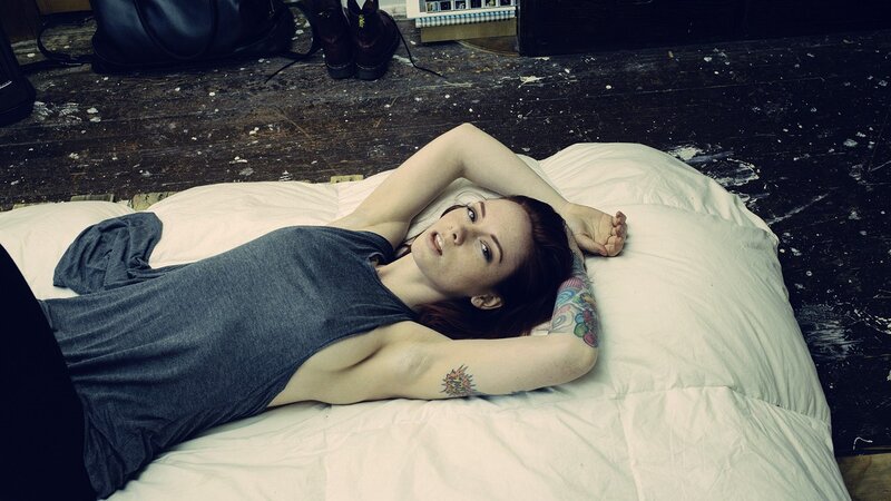 woman with tattoos lying on bed